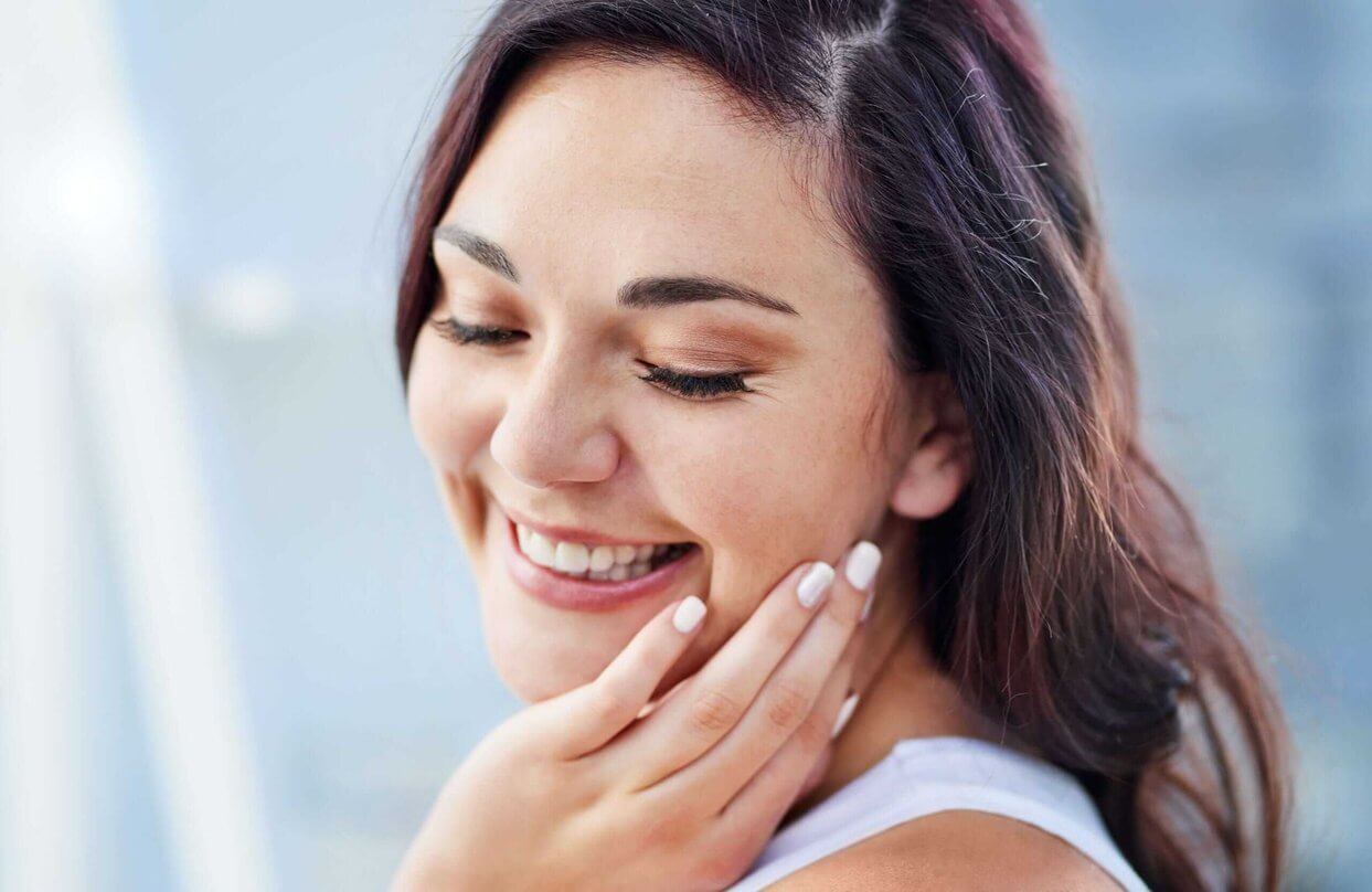 Woman smiling touching her own cheek