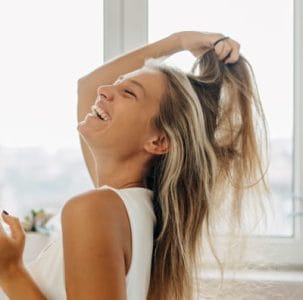a woman joyfully playing with her long, highlighted hair