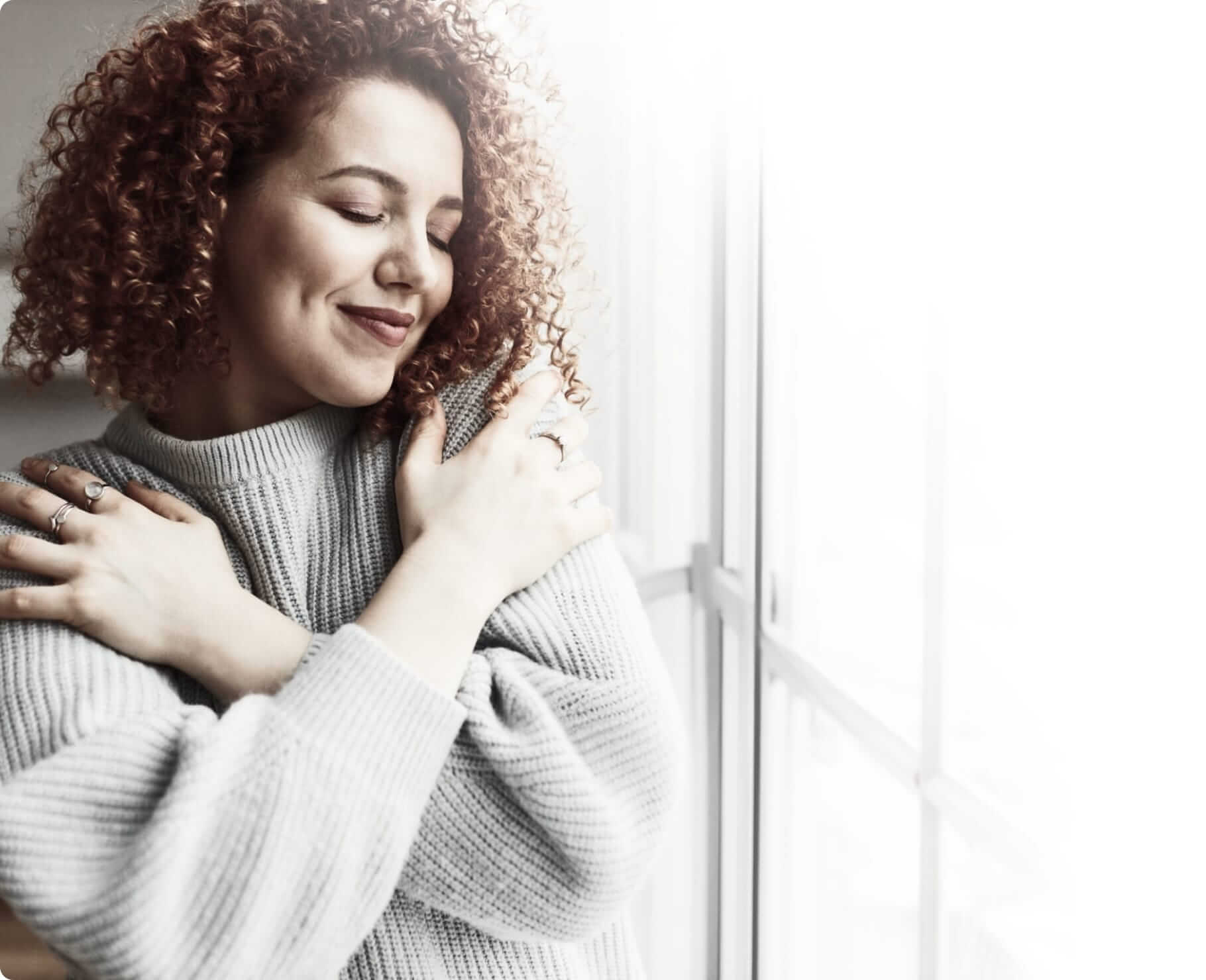 a woman with red curly hair wearing a soft blue sweater