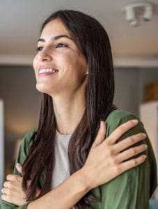 a woman smiling while wearing a green button-down shirt