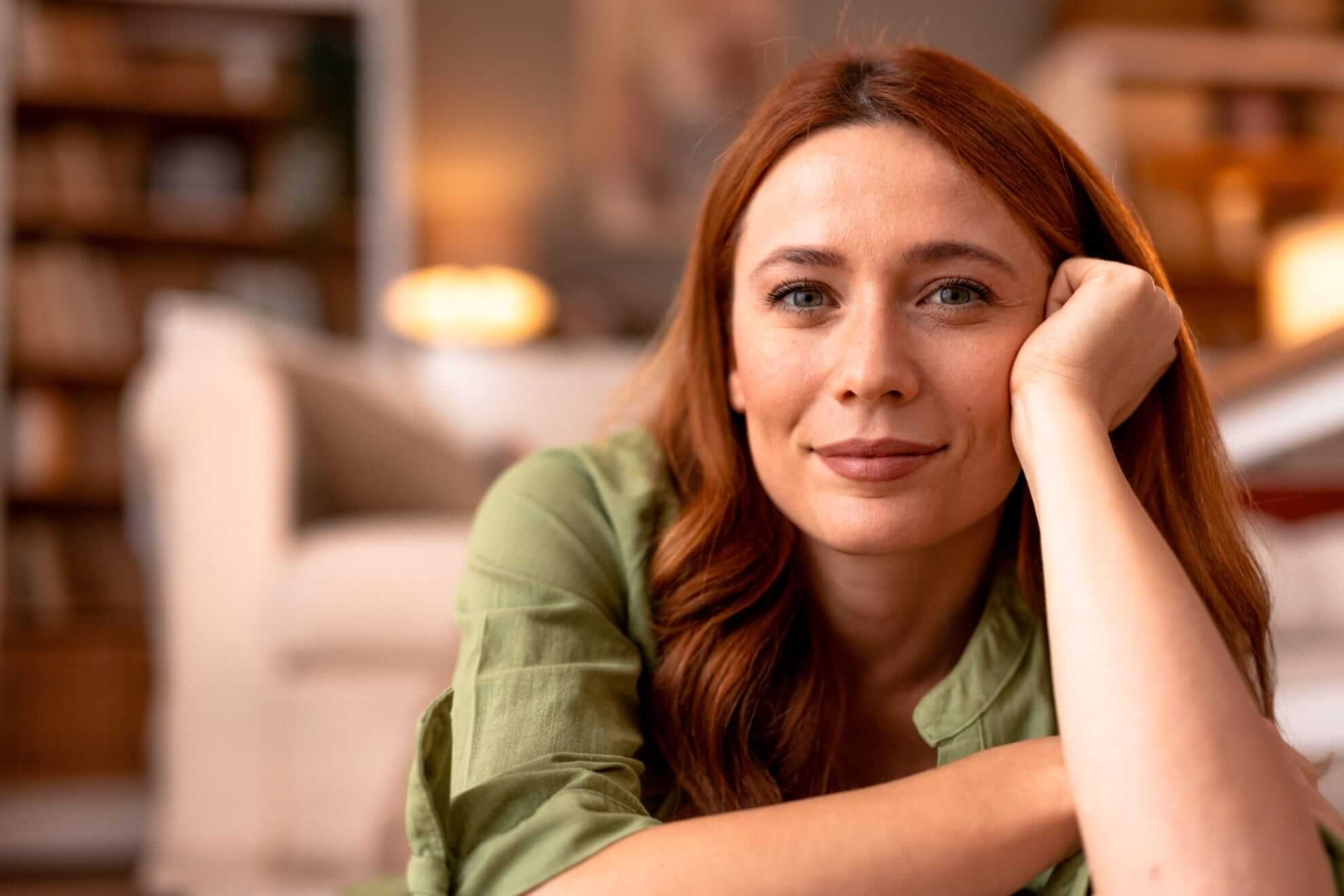 a woman with auburn hair resting hei chin on hei hand 