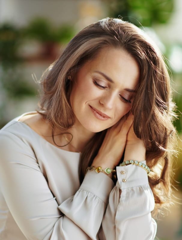 a woman wearing delicate beaded bracelets and a light-colored top with buttoned cuffs
