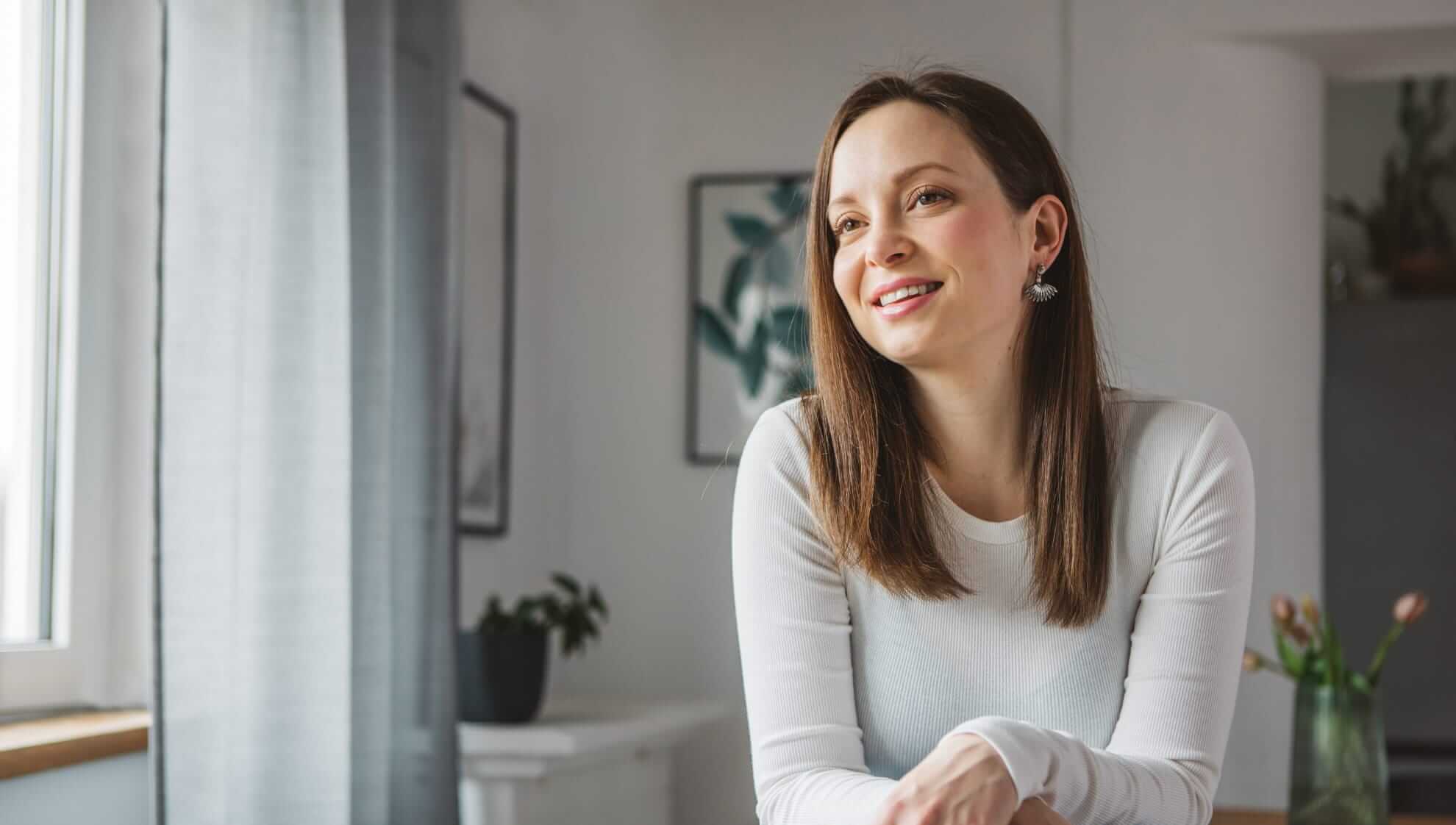 smiley woman wearing a white, long-sleeved ribbed top 
