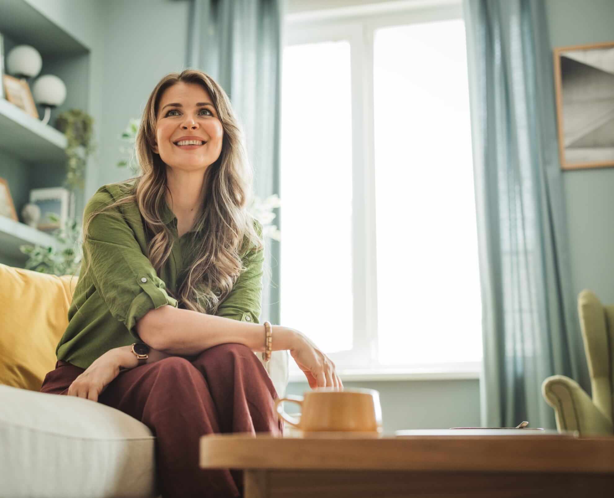 woman smiling and sitting comfortably on a sofa