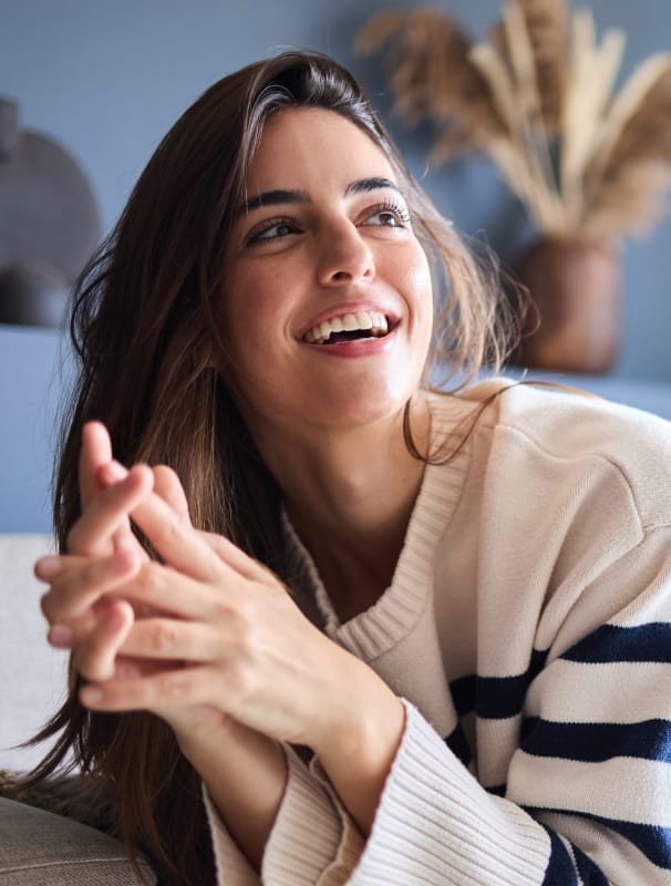 a woman smiling and wearing a cozy, striped sweater