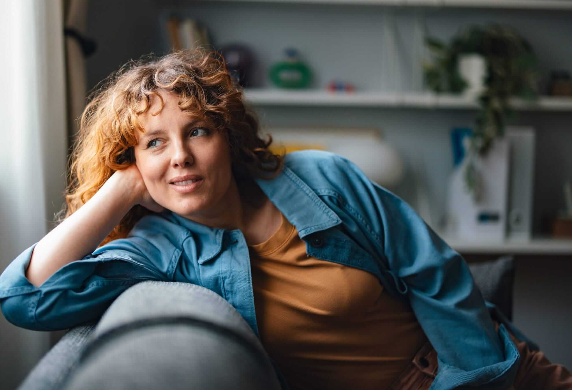 lounging on a grey couch, wearing a casual denim jacket