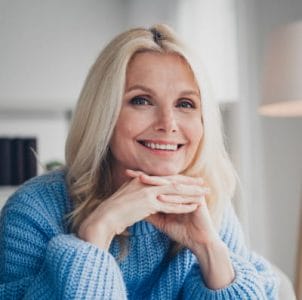 a woman with blonde hair posing in a blue knit sweater