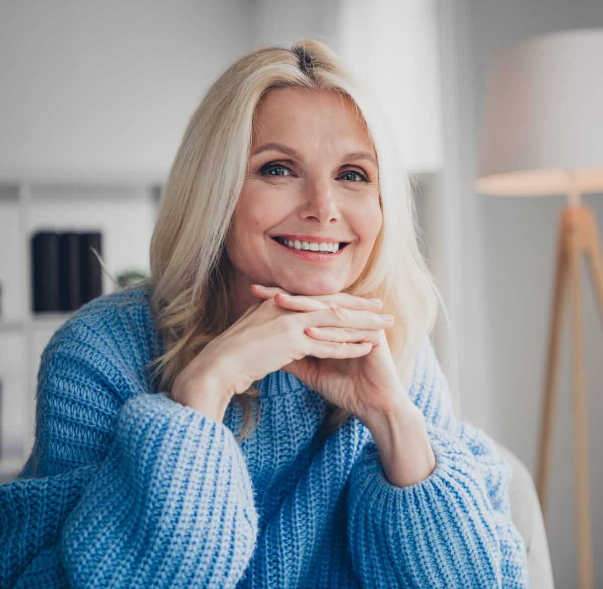 a woman with blonde hair posing in a blue knit sweater