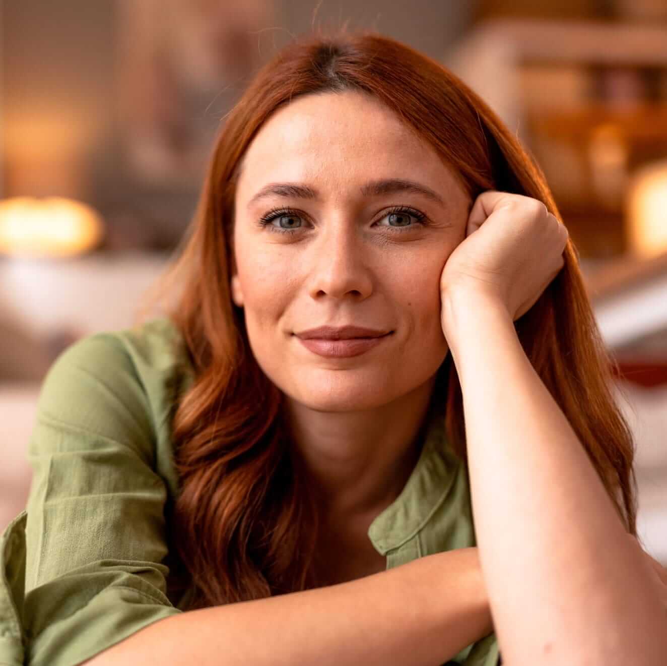 a woman with auburn hair resting hei chin on hei hand